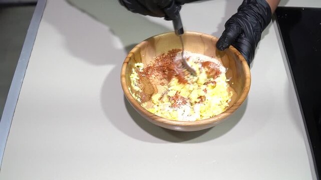 Professional Chef Mixing Spices and Creamy Sauce in Wooden Bowl