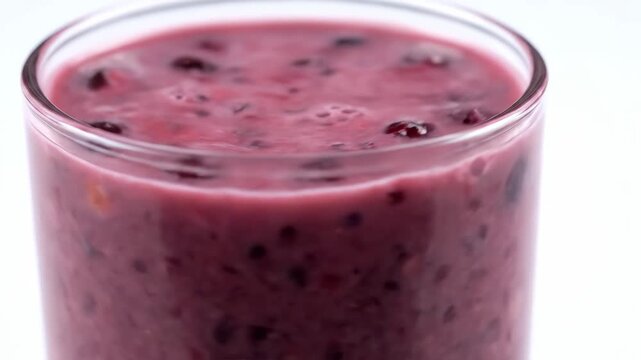 Fresh mixed berry smoothie in glass close-up with vibrant purple swirls and frothy texture for healthy lifestyle