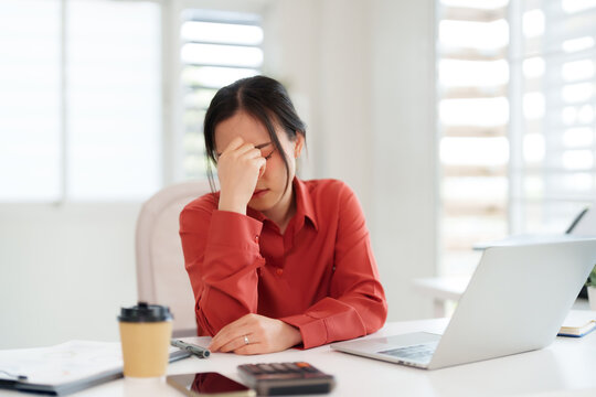 Asian adult businesswoman experiencing work related stress and financial pressure facing challenges in her modern home office environment