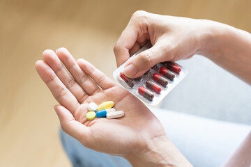 Sick ill asian young woman, girl hand taking tablet pill capsule out from blister pack, painkiller...