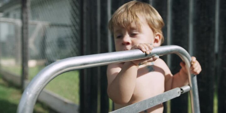 Toddler holding onto a sun lounger frame in the garden