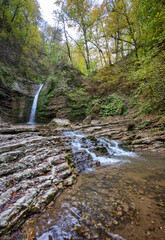 Fototapeta premium Autumn walks along the streambed, fallen and yellowed foliage emphasizes the color of the season.