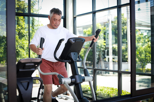 Elderly man maintains his health by doing cardio exercises in a brightly lit gym, reflecting a modern and active lifestyle. Concept of exercising for health in retirement.