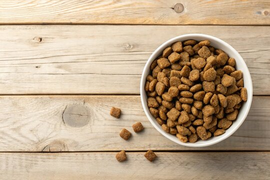 Brown kibble sits in white bowl