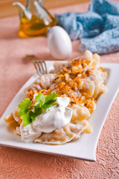A plate with boiled dough vareniki with potato filling and fried onions.
