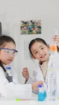 Two Young Asian Girls Perform Bernoulli's Principle Science Experiment in Classroom