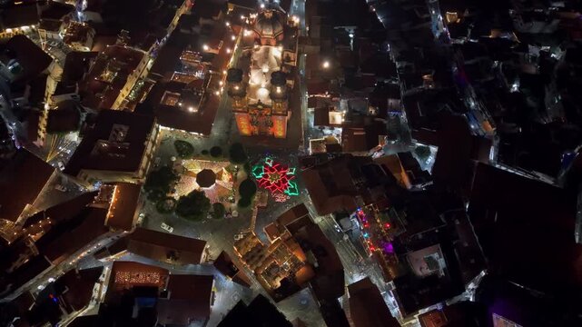 Nighttime aerial view of the Santa Prisca temple and the giant poinsettia in the town of Taxco in Guerrero, Mexico, interconnected and illuminated cobblestone streets