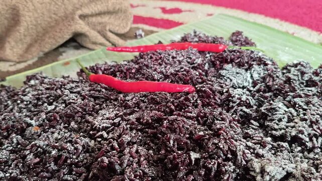 Traditional addition of spices into fermenting black rice, enhancing flavor during fermentation process, showcasing authentic preparation, culture, and natural superfood production.