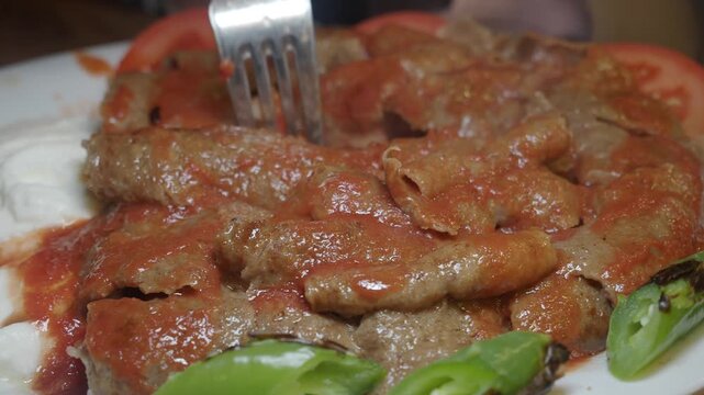 Classic turkish iskender kebab with tomato sauce yogurt and grilled peppers on white plate served in restaurant
