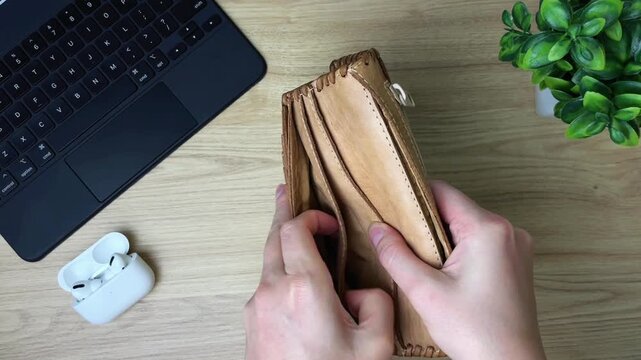 A close-up of a woman's hands checking every pocket of an empty purse. Symbolic of a lack of money, a limited budget, and financial problems in everyday life.