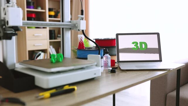 A modern 3D printer is actively creating the letters '3D' in bright green plastic on its build plate