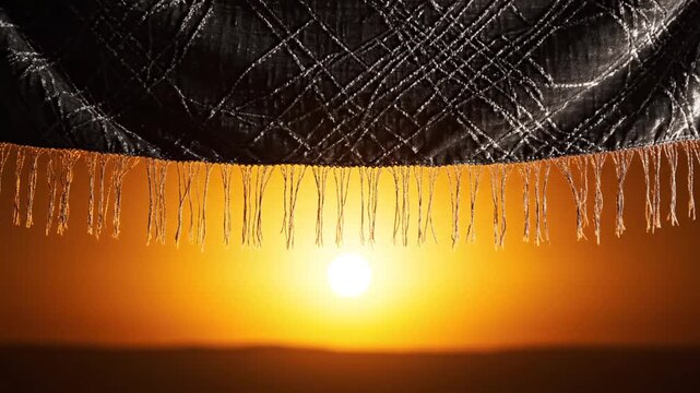 Sunset behind decorative fringe and quilted fabric texture