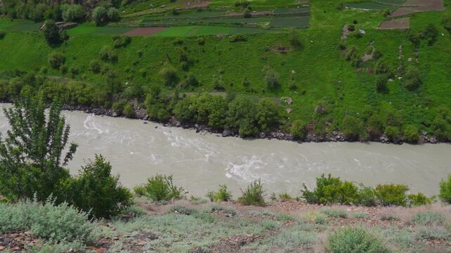 River Chenab flowing between the Himalayan mountain valley as seen from Udaipur village in Lahaul, Himachal Pradesh, India during the summer season. River flows in between the mountain valley.
