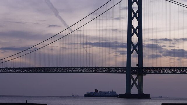 Cargo ship passing under Akashi Kaikyo Bridge at dusk, calm sea and evening sky in Japan
夕暮れの明石海峡大橋を通過する船と穏やかな海
