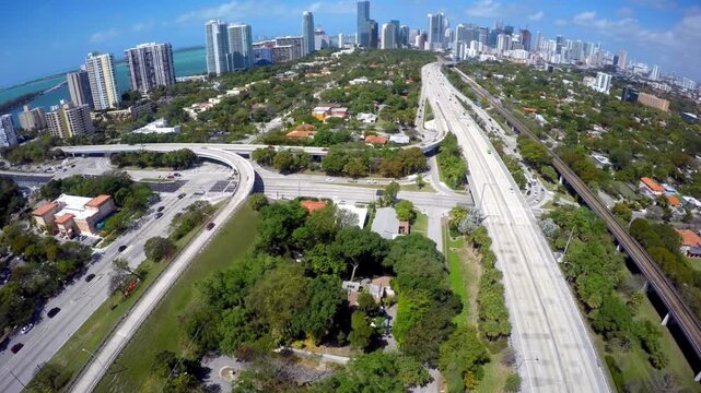 Amazing Aerial view of Miami highway interchange with city skyline and tropical greenery. 
