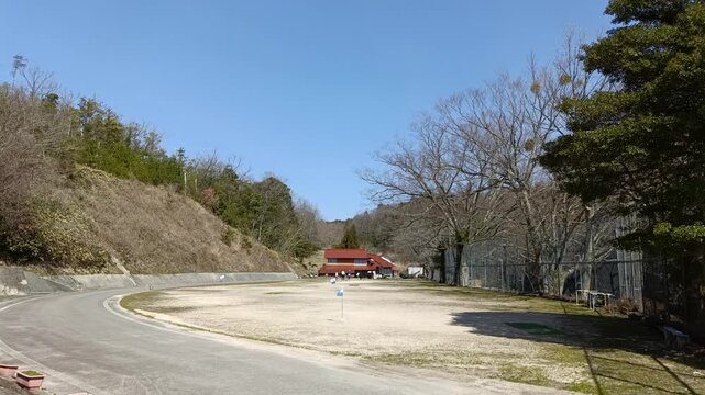 Rural community activity in Japanese countryside, small figures near traditional building