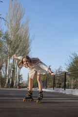 Fototapeta premium A teenage girl rollerblades in a park on a bright sunny day. Concept is to provide children with useful activities during their free time