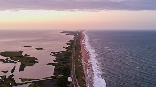 A Narrow Coastal Road Runs Between Calm Marshlands and the Open Sea - Timelapse