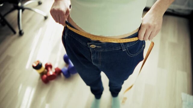 Woman Measuring Waist After Weight Loss. Progress Of Slimming And Result Of Fitness Training At Home
