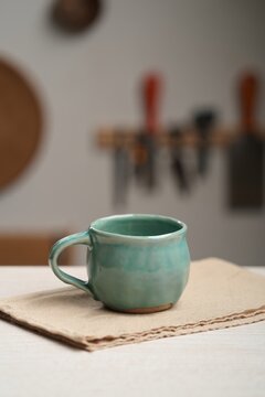 Handmade ceramic mug on artisan work-bench with soft studio lighting and tools