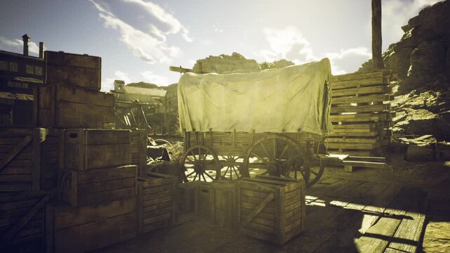 An old wooden wagon covered with a white cloth sits amidst stacked crates in a rustic, sunlit western landscape. Rolling hills and blue skies provide a backdrop to this tranquil setting.