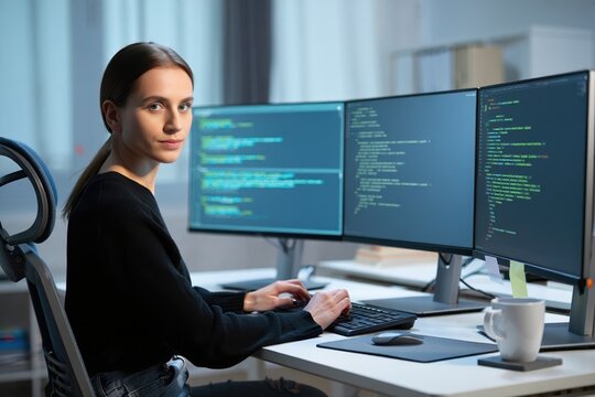 Female programmer debugging multiple code-filled monitors in a modern office