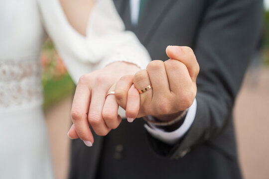 Couple's hands wearing engagement and wedding rings, symbolizing love, commitment, and marriage. A close-up view of joining hands