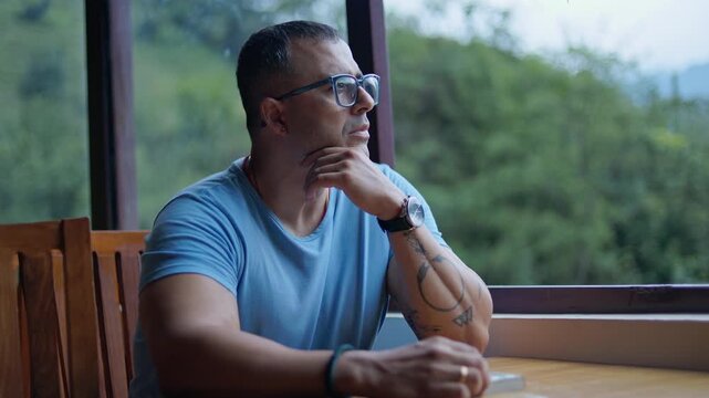 Man spending leisure time in countryside caf&eacute;, sitting quietly and thinking while enjoying outdoor scenery.