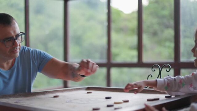 father and daughter enjoying an indoor board game together with a scenic green view in the background.