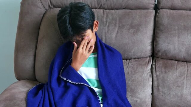 Young boy stirring from sleep with tired and groggy emotions on comfortable gray couch