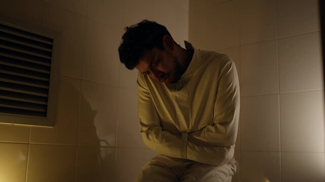 Man in straitjacket in dimly lit cell, capturing isolation and distress