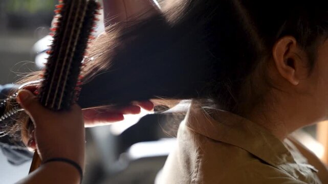 Hair stylist brushes and blow-dries a woman's hair during an outdoor grooming session