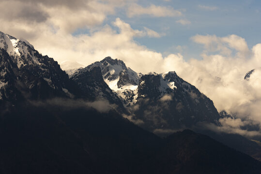 Dramatic clouds partially obscure sun-kissed peaks in the French Alps