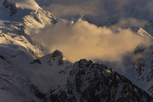 Golden hour light illuminates a massive, glacier-covered mountain face