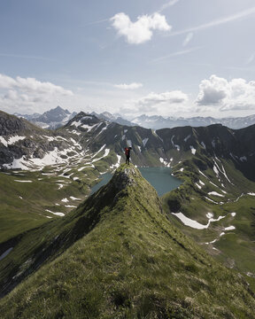 Woman hiking on a trail towards an alpine lake