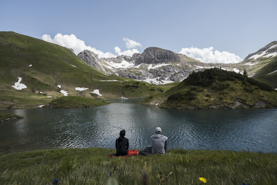 Couple sitting together enjoying the view of an alpine lake
