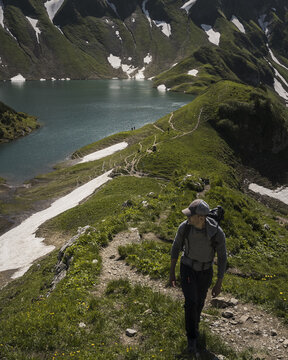 Man hiking on a trail towards an alpine lake