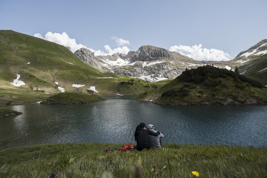 Couple sitting together enjoying the view of an alpine lake