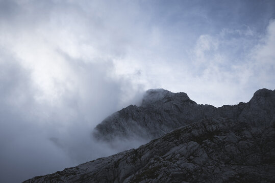 Moody and dramatic view of a mountain peak through fog