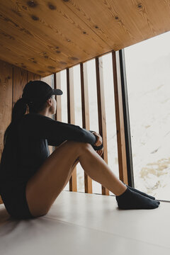 Hiker rests inside a wooden bivouac, looking out the window