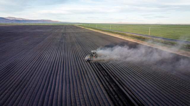 Aerial shot of a tractor tilling vast field in American West.