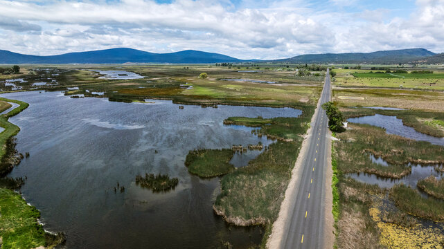 Aerial shot over a road in a wetland setting in American West