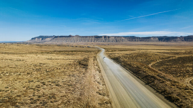 Aerial shot of a truck driving down dusty desert road.