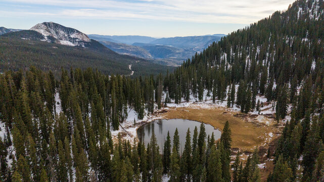 Aerial shot over an alpine lake with snow in the mountains.
