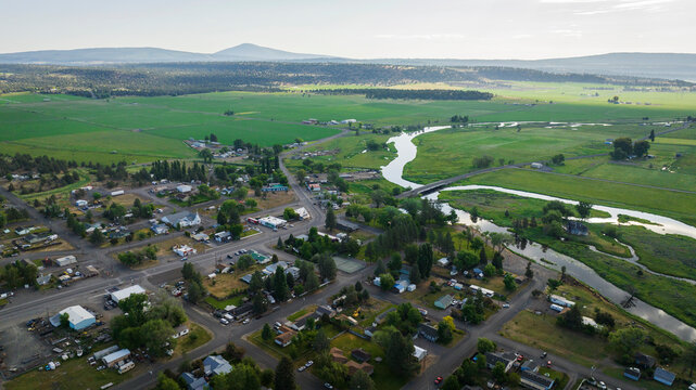Aerial shot over small rural town with river and ag fields.