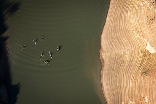 Aerial stright-down view of kayakers in a nearly dry reservoir.