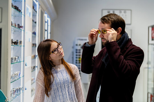 Father and daughter choosing glasses frames in an optician store.