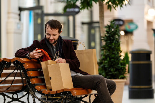 Man sitting  in shopping mall and checking items from  bag.