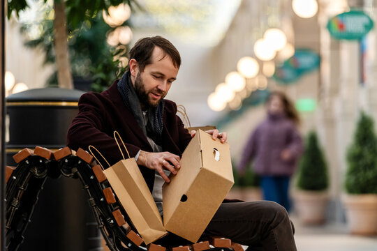 Man Sitting on Bench in Mall Checking Purchase Bags