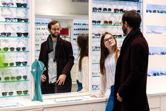 Father and daughter choosing glasses frames in an optician shop.